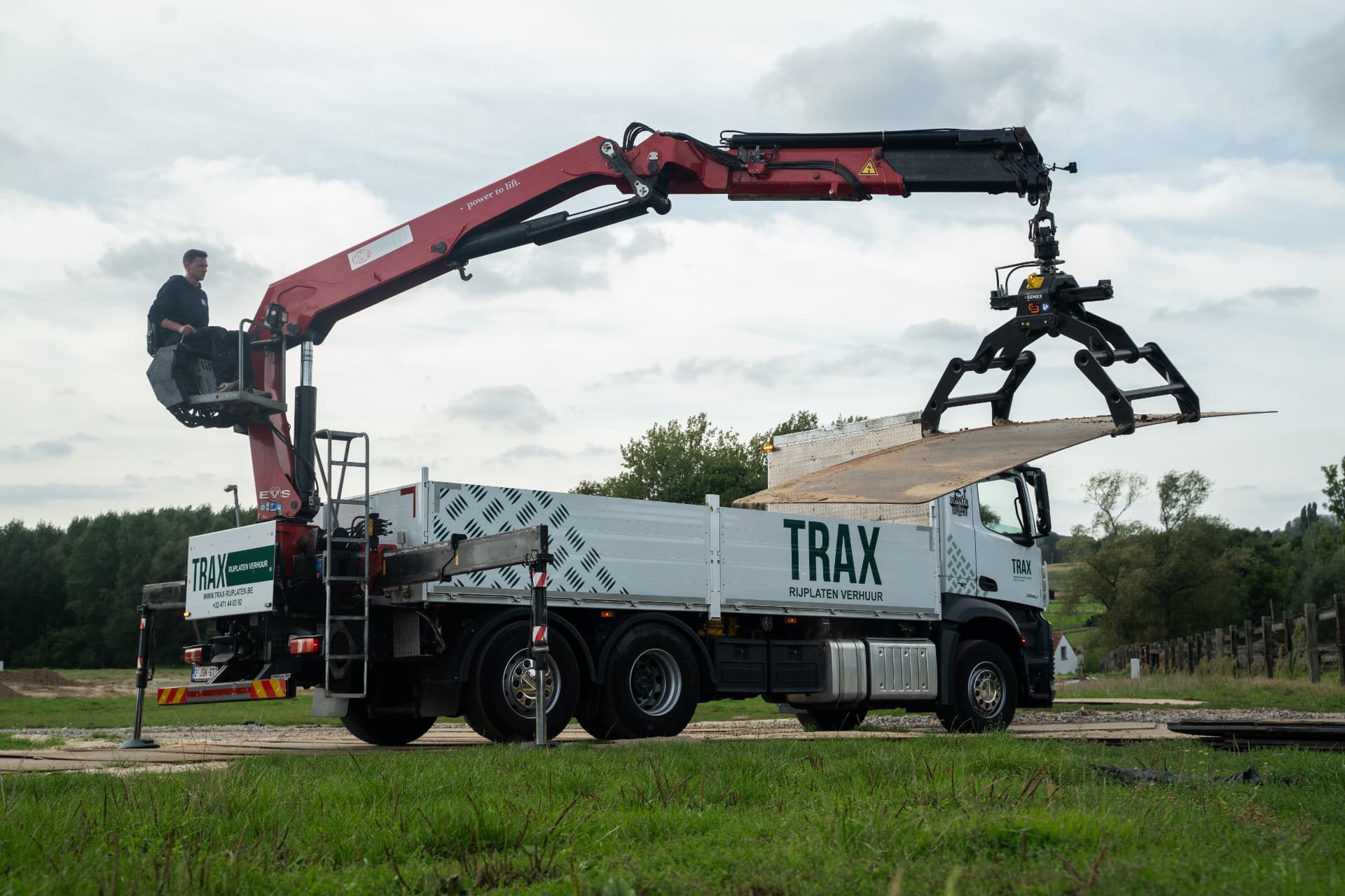 TRAX vrachtwagen met kraan legt stalen rijplaten uit op een werf